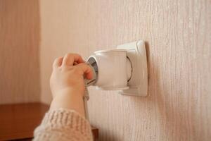 le enfant pièces avec un sortie, tire le sien mains à il, des bâtons le sien des doigts. le enfant est dans danger à maison. bébé les doigts dans le prise. photo