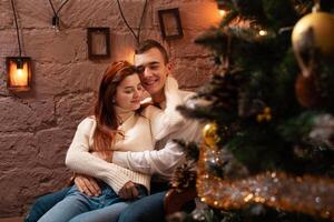 une gars avec une fille est célébrer Noël. une aimant couple jouit chaque autre sur Nouveau années l'amour histoire. Noël décorations dans le photo studio posant pour des modèles