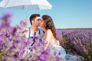 une couple dans l'amour en dessous de une blanc parapluie sur une lavande champ l'amour photo