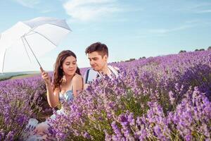 une couple dans l'amour en dessous de une blanc parapluie sur une lavande champ l'amour photo