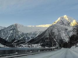 conduire au lever du soleil à travers les montagnes et les forêts en norvège. photo
