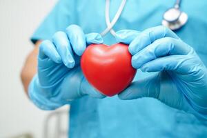 femme médecin asiatique tenant un coeur rouge pour la santé à l'hôpital. photo