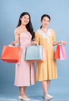 deux jeunes femmes asiatiques tenant un panier sur fond bleu photo
