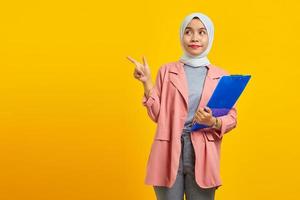 portrait d'une belle femme avec un dossier debout et pointant vers l'extérieur sur fond jaune photo