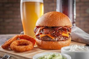 délicieux hamburger au bacon avec rondelles d'oignon et bière. photo