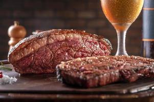 rumsteck tranché grillé avec deux verres de bière sur une planche à découper en bois. viande de boeuf en marbre - picanha brésilien. photo