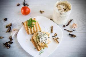 frit pain pain grillé avec fromage propager avec bouilli séché champignons sur une en bois tableau. photo