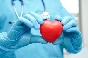 femme médecin asiatique tenant un coeur rouge pour la santé à l'hôpital. photo