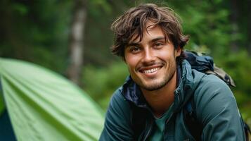 ai généré portrait de souriant homme avec sac à dos permanent dans de face de camping tente photo