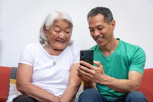 adulte fils enseignement le sien personnes âgées mère de Japonais origine Comment à utilisation une mobile téléphone. photo