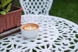 café chaud latté avec fleur forme dans blanc tasse sur rétro table photo