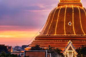 bouddhistes montée en haut à lumière décoration le d'or pagode phra pathom chedi sur le coucher du soleil ciel dans annuel de fête à Nakhon pathom photo