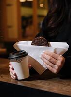 femme en portant une agresser de café et flocons d'avoine biscuits dans sa mains dans café magasin photo