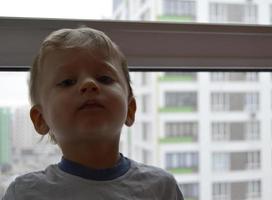 beau petit garçon avec un visage d'enfant posant un photographe près de la fenêtre photo