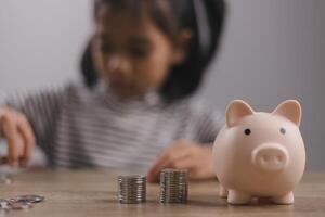 petite fille asiatique économisant de l'argent dans une tirelire, apprenant à économiser, enfant économisant de l'argent pour l'éducation future. concept d'argent, de finances, d'assurance et de personnes photo