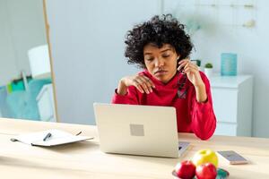 africain américain fille en utilisant portable à Accueil Bureau à la recherche à écran dactylographie bavardage en train de lire l'écriture e-mail. Jeune femme ayant virtuel réunion en ligne bavarder vidéo appel conférence. travail apprentissage de Accueil photo