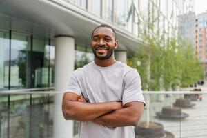 content africain américain homme souriant Extérieur. portrait de Jeune content homme sur rue dans ville. de bonne humeur joyeux Beau la personne gars à la recherche à caméra. liberté bonheur insouciant content gens concept photo