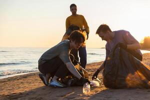 Terre journée. bénévoles militants recueille des ordures nettoyage de plage côtier zone. femme et mans met Plastique poubelle dans des ordures sac sur océan rive. environnement préservation côtier zone nettoyage photo