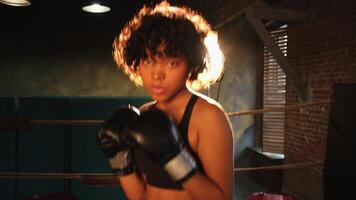 femmes soi la défense fille pouvoir. africain américain femme combattant perforation avec boxe gants à caméra. en bonne santé fort fille perforation formation poinçons à la recherche concentré droit. en forme corps faire des exercices photo