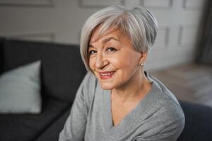 portrait de sur de soi élégant européen milieu vieilli Sénior femme. plus âgée mature Années 60 Dame souriant à maison. content attrayant Sénior femelle à la recherche caméra proche en haut visage photo du visage portrait. content gens