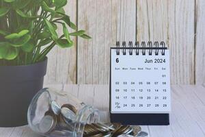 juin 2024 bureau calendrier avec empiler de pièces de monnaie et mis en pot plante sur en bois bureau. photo