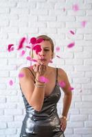 femme caucasienne soufflant des confettis colorés dans l'air photo