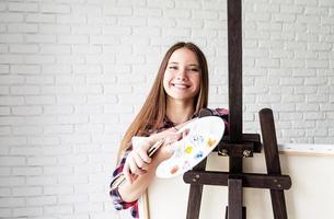 belle artiste femme souriante avec palette de couleurs et pinceaux photo