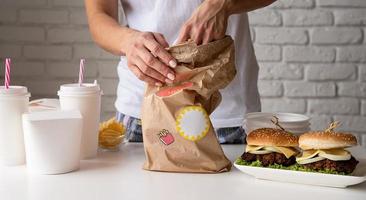 femme en vêtements de maison déballant de la nourriture livraison à domicile avec des hamburgers, des boîtes de nouilles et des boissons photo