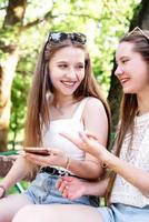 deux femmes heureuses parlant dans le parc à l'aide d'un téléphone portable photo