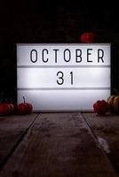31 octobre caisson lumineux dans la pièce sombre avec des citrouilles sur plancher en bois photo