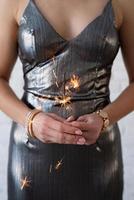 femme dans une robe de soirée tenant un cierge magique dans ses mains