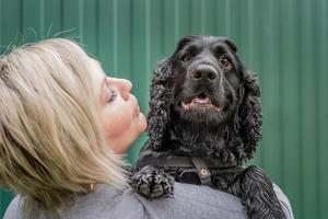 Jeune femme tenant son chien cocker sur fond vert à l'extérieur photo