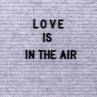 les mots l'amour est dans l'air sur un tableau à lettres en feutre gris photo