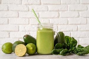 smoothie à l'avocat et aux épinards en vue de face de pot Mason sur fond de mur de briques blanches photo