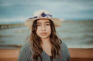portrait de magnifique Latin fille dans chapeau sur le jetée. portrait de Jeune touristique femme dans chapeau sur une jetée photo