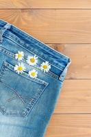 deux fleurs de camomille dans une poche de jean. marguerite sur fond de jeans bleu. carte de voeux d'été