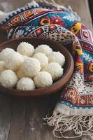 ai généré sucré élégance beijinho noix de coco truffes sur une à motifs folkloriques nappe de table photo