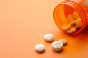 pilules médicales de couleur blanche se déversant sur fond orange photo