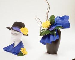 une noir vase avec fleurs et une chapeau photo