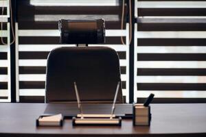 lieu de travail de bureau d'affaires. lieu de travail pour le chef, le patron ou d'autres employés. table et chaise confortable. lumière à travers les stores à demi ouverts photo