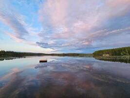 nager île dans Suède sur une Lac à le coucher du soleil. des nuages réfléchi dans le l'eau. photo