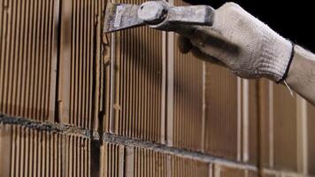 proche en haut de une homme martelage le mur fabriqué de céramique blocs à le construction placer. Stock images. ouvrier dans protecteur gants fabrication une trou dans le mur. photo