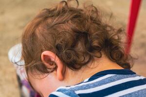 retour vue de le tête de une bébé avec légèrement frisé lumière marron cheveux photo