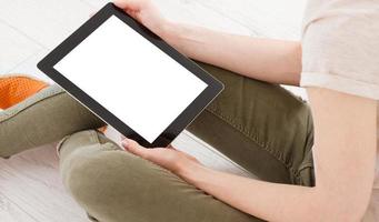 Teen woman girl using a tablet pc assis sur le sol dans un salon , touchant un écran blanc photo