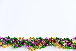 fond de mardi gras. perles dorées, vertes et violettes sur fond blanc. symbole du mardi gras. photo