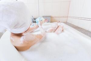 magnifique fille douche et la lessive mains dans baignoire. photo