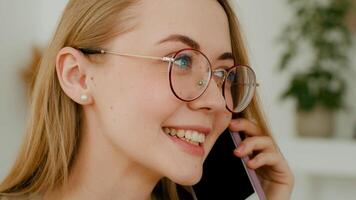 proche en haut femelle visage souriant femme d'affaires dans des lunettes répondre appel. photo du visage caucasien positif femme parlant téléphone avec ami partager nouvelles potins répondre cellule communiquer fille avec téléphone intelligent parler