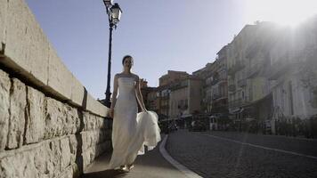 jeunes mariés en marchant près le fontaines. action. magnifique gens ensemble avec une la mariée dans une blanc serré robe et une homme dans touristique des endroits près le rivière avec garé navires. photo