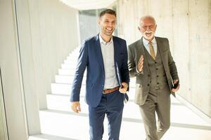 mature homme d'affaire et le sien Jeune collègue discuter financier rapport dans le Bureau couloir photo