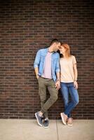 souriant Jeune couple dans l'amour dans de face de maison brique mur photo